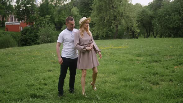 Man with a Woman Blonde in a Dress Dance on a Green Field in Nature in Summer
