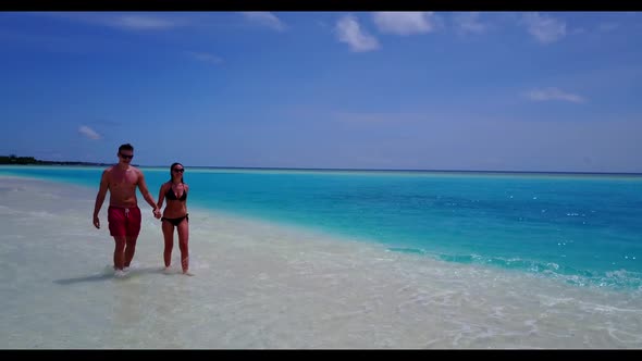 Guy and girl in love on beautiful tourist beach journey by aqua blue ocean with white sandy backgrou