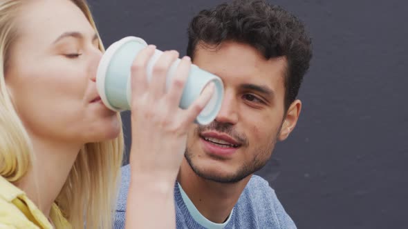 Side view of Caucasian couple drinking a takeaway coffee sitting on stairs