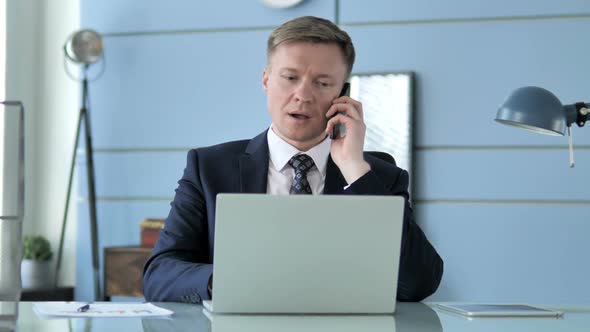 Businessman Talking on Phone at Work