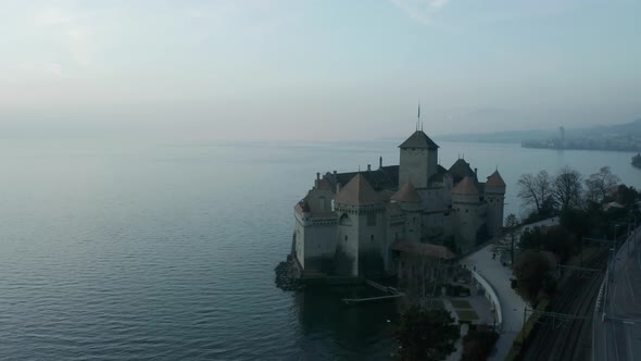 Aerial of Château de Chillon overlooking a misty Lake in Switzerland