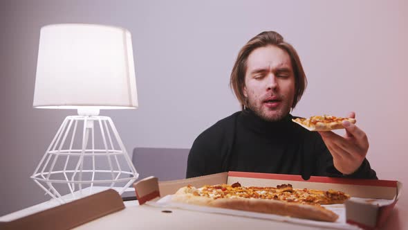 Young Caucasian Man Eating Slice of Pizza While Having a Toothache