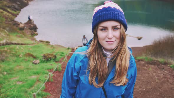 Portrait of Young Tourist Woman in Jacket and Hat Enjoying Beautiful View of Kerid Lake of Iceland
