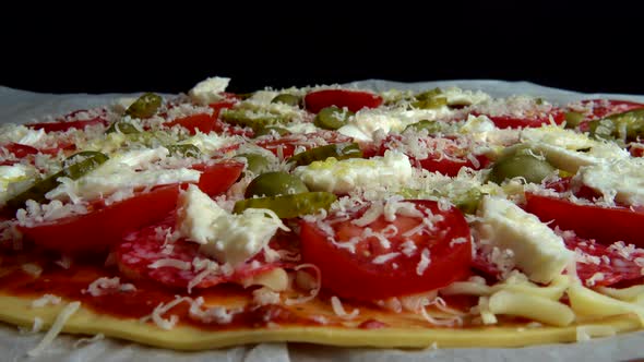 Spinning pizza with mozzarella cheese, olives, pickled cucumbers, tomatoes, parmesan cheese