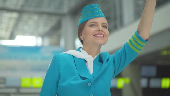 Portrait of Beautiful Mid-adult Caucasian Woman in Stewardess Uniform Waving Away and Smiling