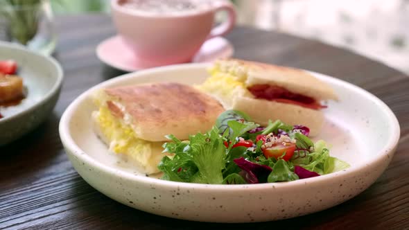 Sandwich with Egg Cheese and Pepperoni with Fresh Green Salad on White Plate