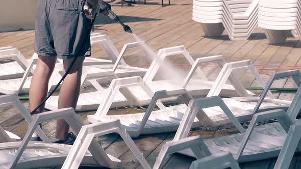 Beach Worker Washes the Beach Loungers