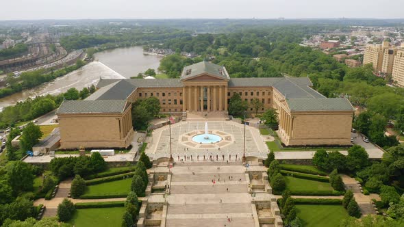 Aerial drone view moving backward showing the Philadelphia Museum of Art surrounded by bright green