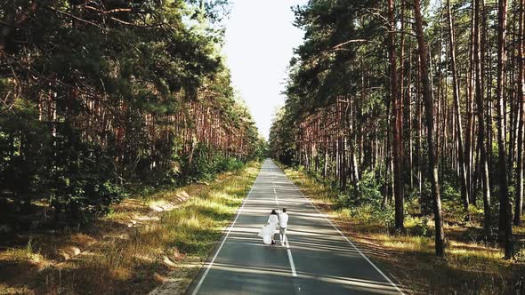 A Cheerful Young European Couple is Walking in a Picturesque Place in the Pine Forest Aerial View