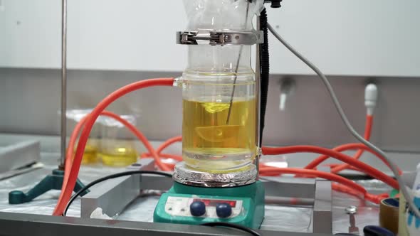 Twisting Motion of Mechanical Stirrer with Yellow Liquid in Glass Beaker on Hot Plate in Scientific