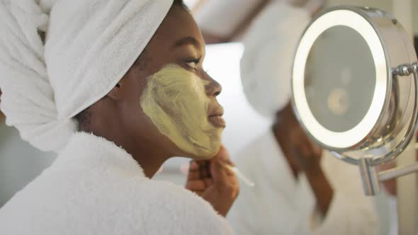 Profile of african american attractive woman applying face mask in bathroom