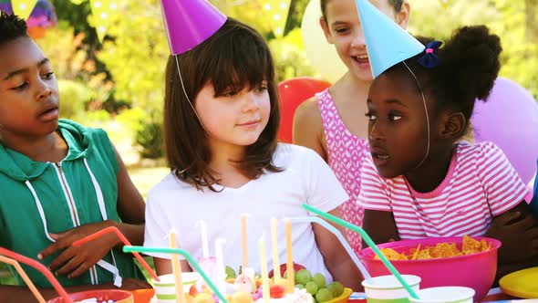 Kids standing near table laid with food and celebrating a birthday