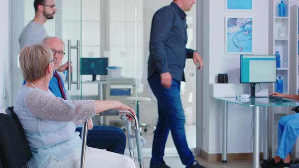 Disabled Senior Woman Talking with Old Man in Hospital Waiting Room