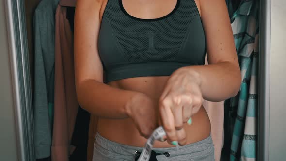 Girl With a Beautiful Figure Measures Her Waist with a Measuring Tape