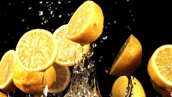 Pieces of Juicy Lemons with Splashes of Water Fly Up and Fall Down