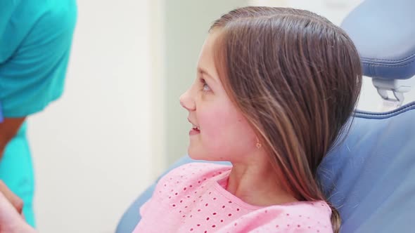 Girl shaking hands with dentist while sitting in the chair