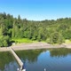 Dock pier with lush green trees on ocean lake coast, blue sky reflection on calm green water - VideoHive Item for Sale
