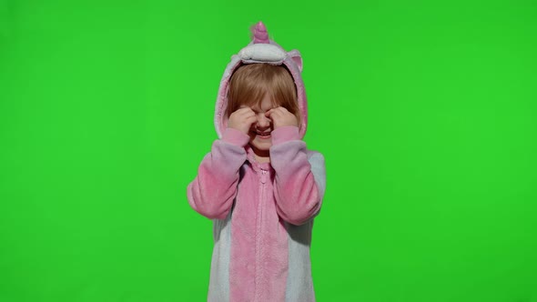 Little Blonde Child in Unicorn Costume Crying Wiping Tears with Her Hands on Chroma Key Background