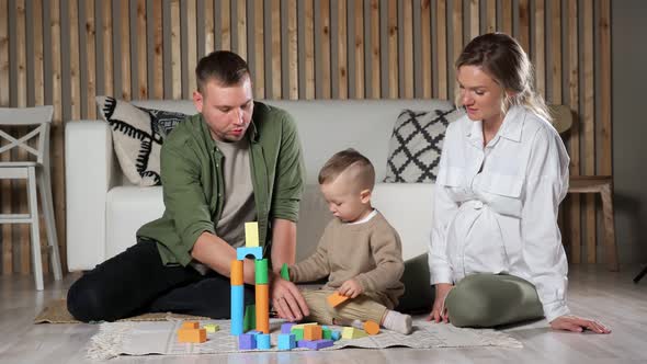 Parents and Little Son Play with Colorful Wooden Blocks