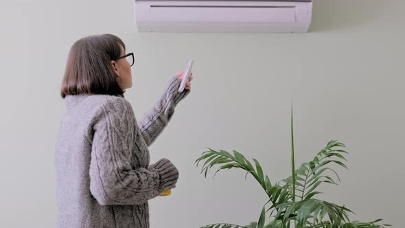 Woman in Sweater Heating Home Turning on Air Conditioner to Heat Air