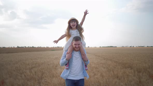 Portrait of Happy Fatherhood, Young Cheerful Father Runs with His Little Cute Daughter on Shoulders