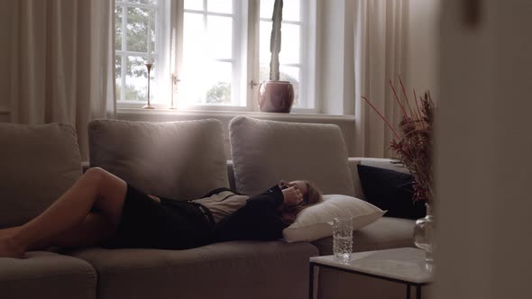 Businesswoman In Suit Relaxing On Sofa And Speaking Smartphone