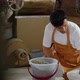 young man working in a coffee roaster is scooping coffee beans, weighing them for roasting, - VideoHive Item for Sale