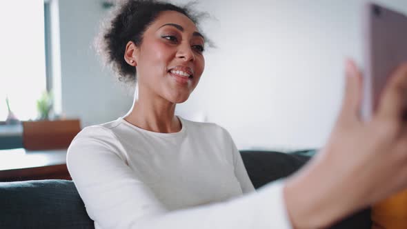 Smiling African pregnant woman talking by video call on phone