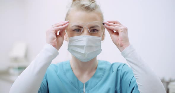 Female Doctor Wearing Protective Mask on Face and Put Glasses. Doctor at Healtcare Clinic