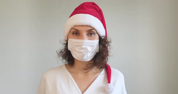 Young Woman in Medical Mask and Santa Claus Hat Dancing and Having Fun. Close Up of Female in