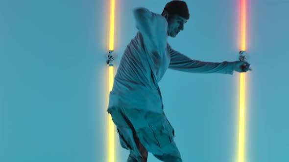 Stylish Young Man with Tattoos Performs Cool Street Dance Against Backdrop of Bright Neon Lights