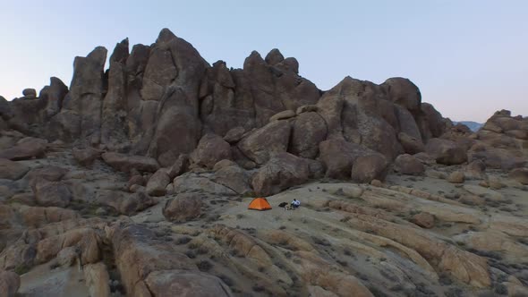 Aerial shot of a young man backpacker camping with his dog in a mountainous desert.