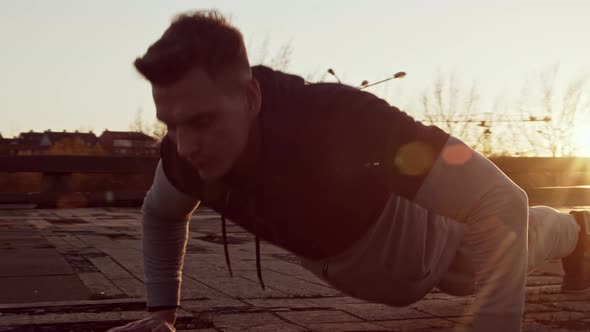 Young and fit man having evening workout outdoor. Urban sunset background.