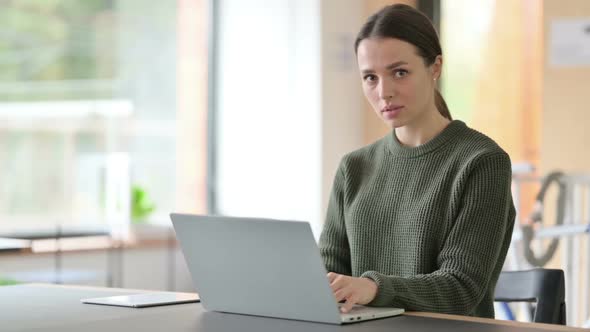 Young Woman with Laptop Shaking Head in Denial No