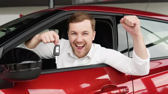 Happy Man Sits in New Car in Shop Dealership and Celebrate Purchase of New Vehicle