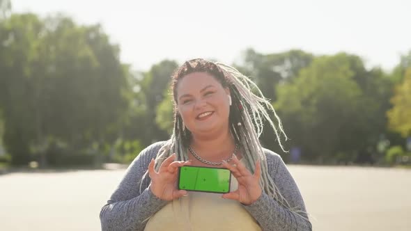 Young Pretty Fat Woman Portrait with Dreads Showing Green Screen Phone To Camera. Beautiful Stout