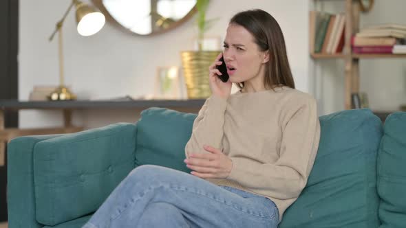 Young Woman Angry on Smartphone on Sofa