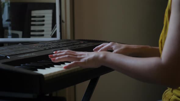 Ultra High Definition Slow motion close up video of an Asian woman playing on a keyboard. The focus 