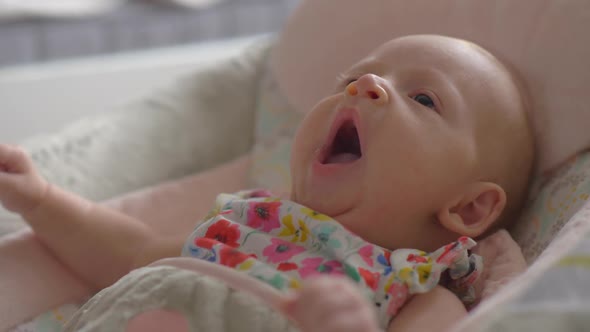 Baby Girl of Two Months Lying in Bouncy Seat and Yawning