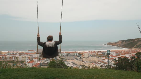 Child Swinging and Looking at Ocean