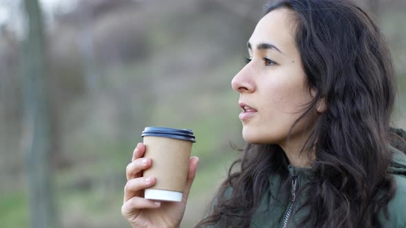 Young attractive woman drink a coffee with joy in cloudy day