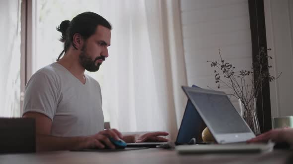 A young man and a young girl are working in front of laptops in their bright apartment.