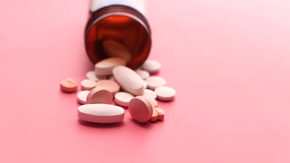  White Pills Spilling on Pink Background with Copy Space 