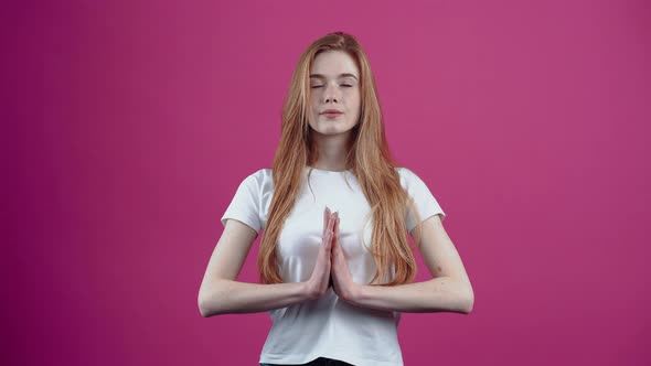 Portrait of a Beautiful Young Woman Meditating with Her Hands Clasped to Her Chest