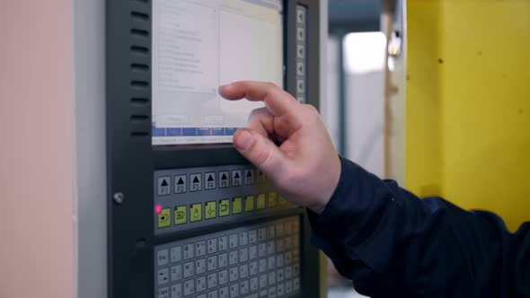 The Hand Presses the Buttons on the Control Panel of the CNC Machine alt
