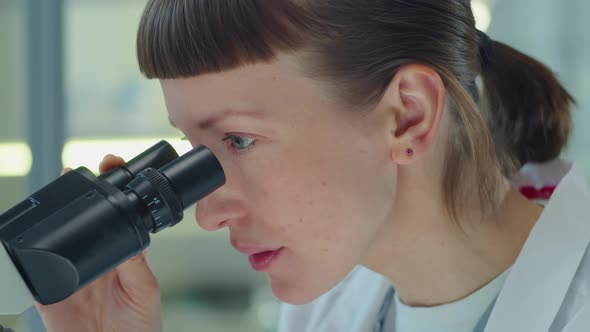 Woman Working with Microscope in Lab