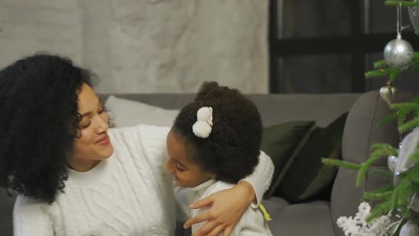 Portrait of Happy African American Mom and Little Daughter Decorate Christmas Tree with Festive Toys