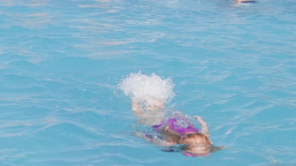 Littlel Girl in Swimming Pool Child Having Fun Sitting on Blue Swimming Ring Playing Under Water