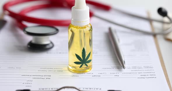 Marijuana Oil in Bottle with Stethoscope Lie on Medical Documents Slow Motion  Movie