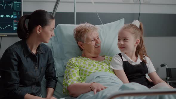 Ill Pensioner Enjoying Visit From Niece and Daughter in Hospital Ward Bed